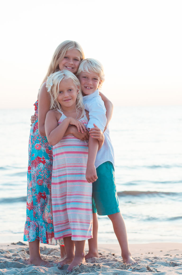 brother and sisters hugging by beach